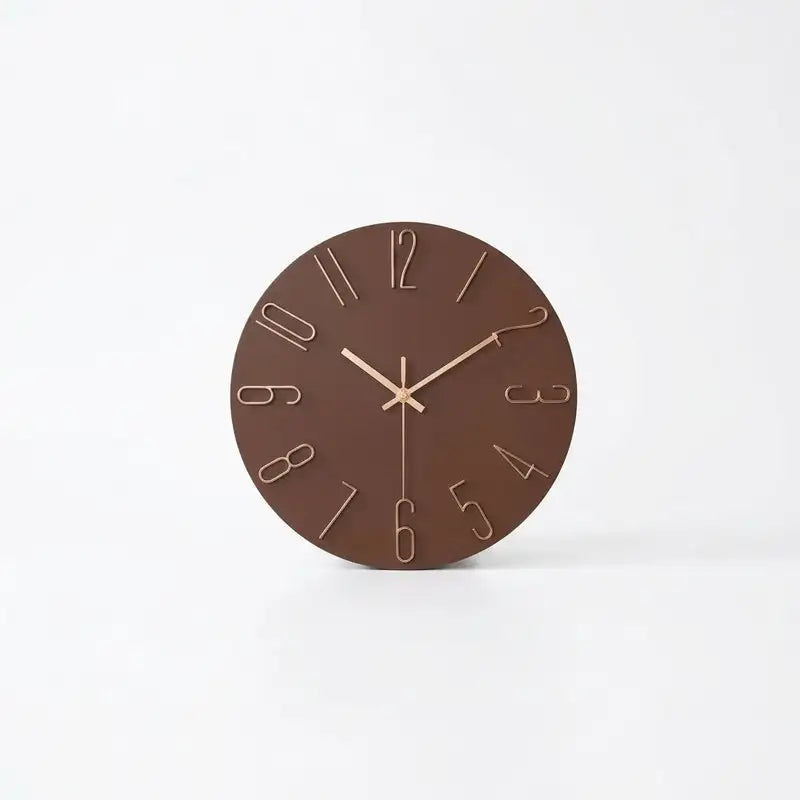 A minimalist round wall clock with a dark brown face and light beige numerals and hands.