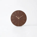 A minimalist round wall clock with a dark brown face and light beige numerals and hands.
