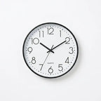 A minimalist quartz wall clock with a black frame, white face, and black numerals and hands.