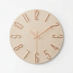 A minimalist round wall clock with a light natural wood face and rose gold metal numerals and hands.